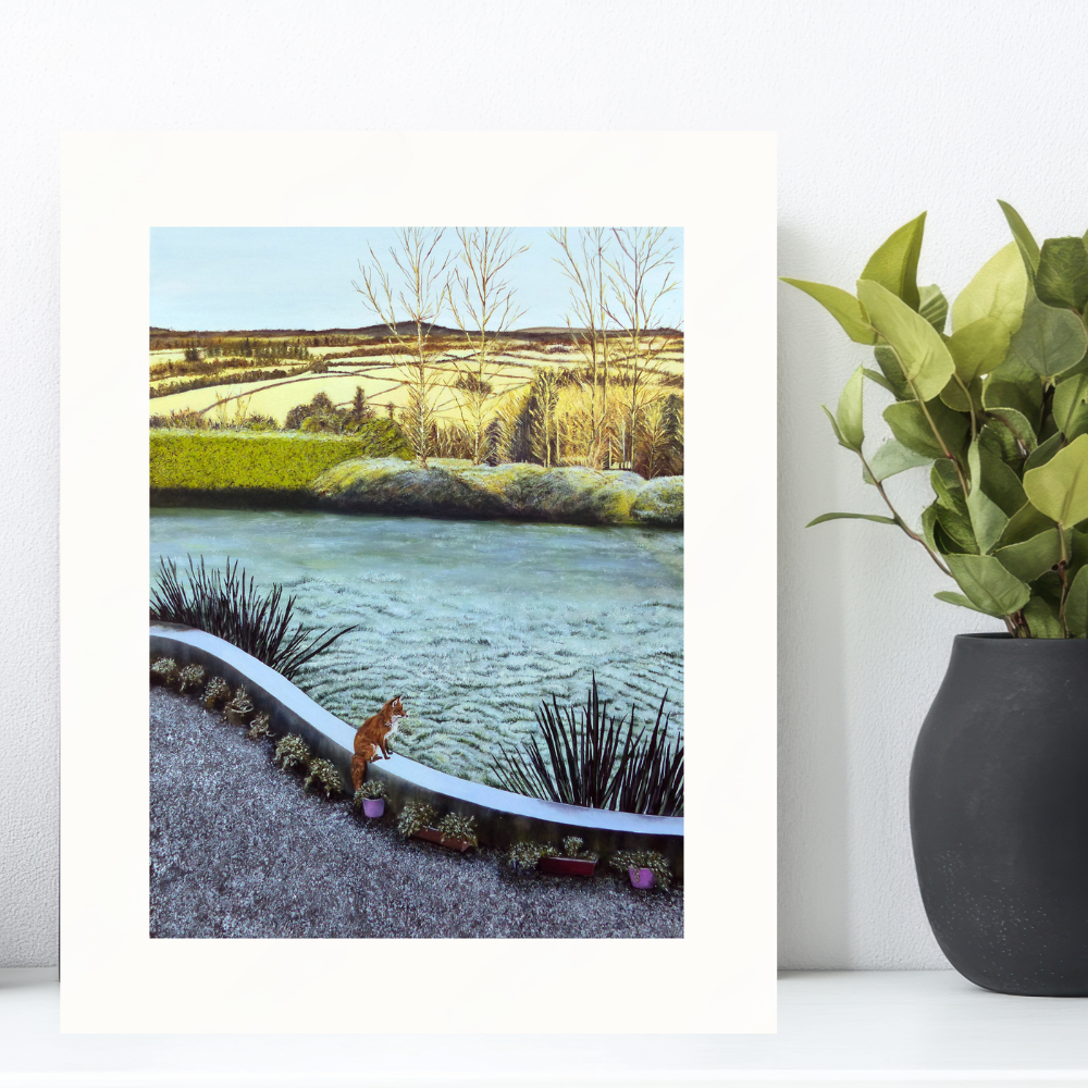 Mounted print of a wintery landscape featuring a fox overlooking a frosted garden with distant trees and fields